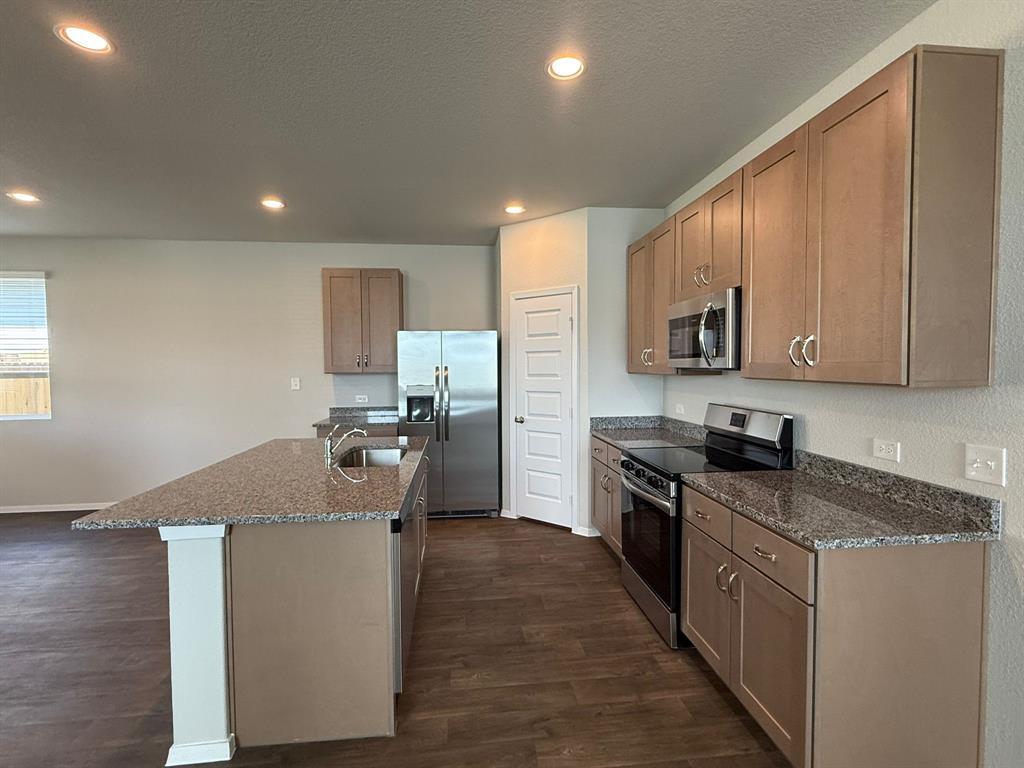 2617 Totley Road Pflugerville, TX 78660 - Photo 12 of 38 Kitchen with stainless steel appliances, dark stone countertops, dark wood-style flooring, recessed lighting, and a textured ceiling