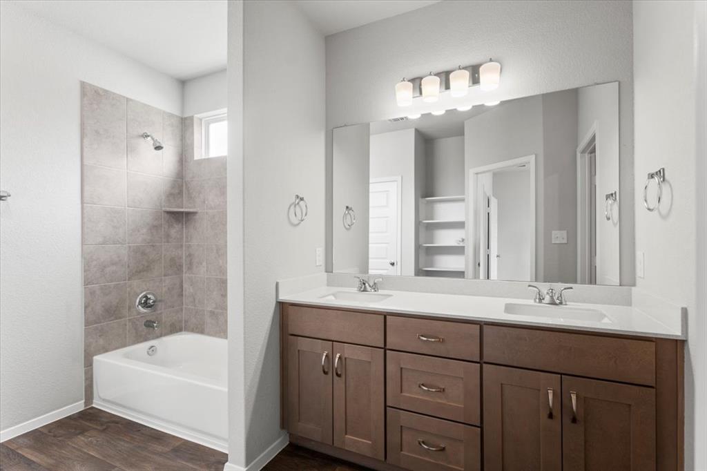 2617 Totley Road Pflugerville, TX 78660 - Photo 19 of 38 Bathroom featuring shower combination, double vanity, and dark wood finished floors