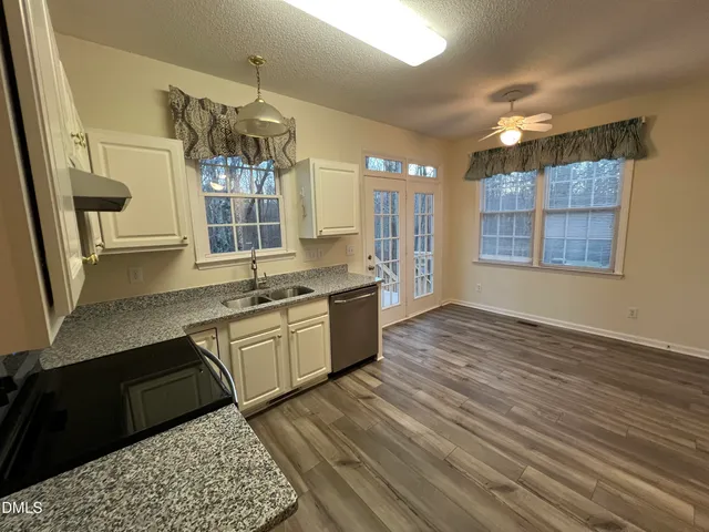 a large kitchen with stainless steel appliances granite countertop a sink dishwasher a stove a dining table and chairs with wooden floor