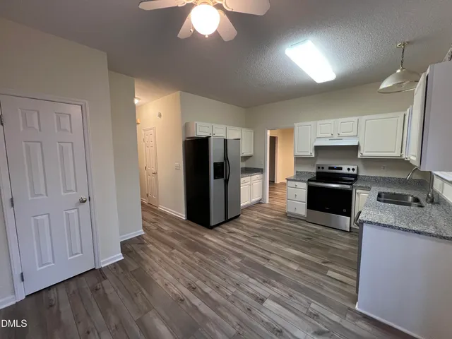 a kitchen with granite countertop a refrigerator and a stove top oven