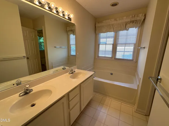 a bathroom with a tub sink and mirror