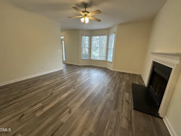 a view of an empty room with wooden floor and a window