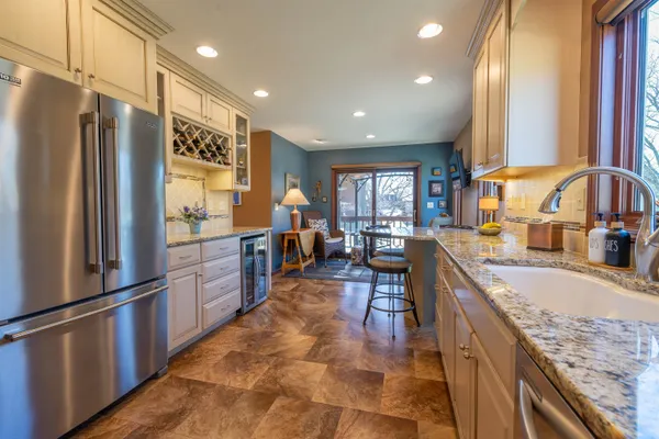 a kitchen with stainless steel appliances granite countertop a refrigerator a sink dishwasher a stove and a dining table with wooden floor
