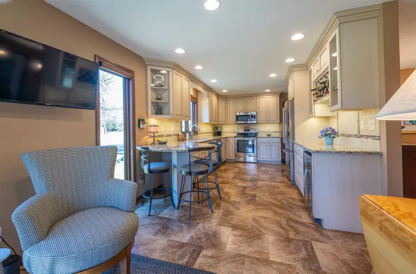 a living room with stainless steel appliances kitchen island granite countertop furniture and a wooden floor