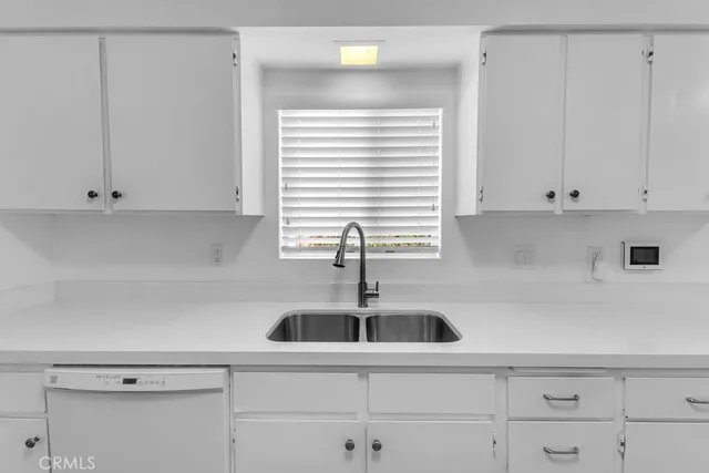 a kitchen with white cabinets and window