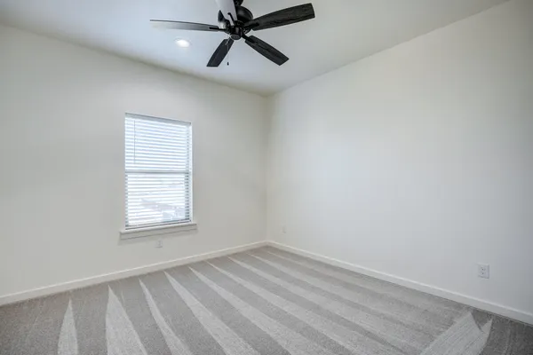 an empty room with a ceiling fan and window