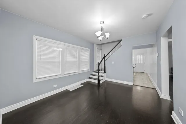 an empty room with wooden floor chandelier and windows