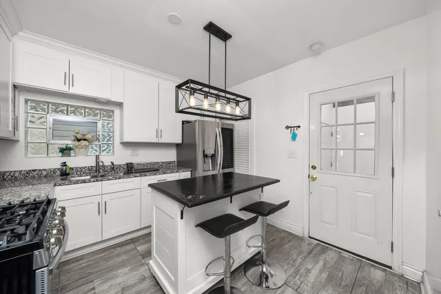 a kitchen with granite countertop a sink a stove and refrigerator