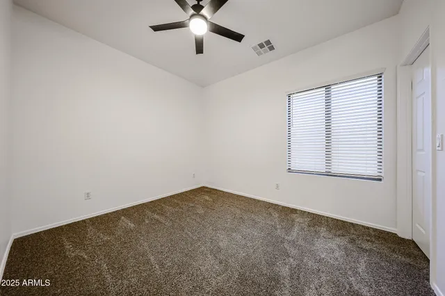 an empty room with a window and a fan