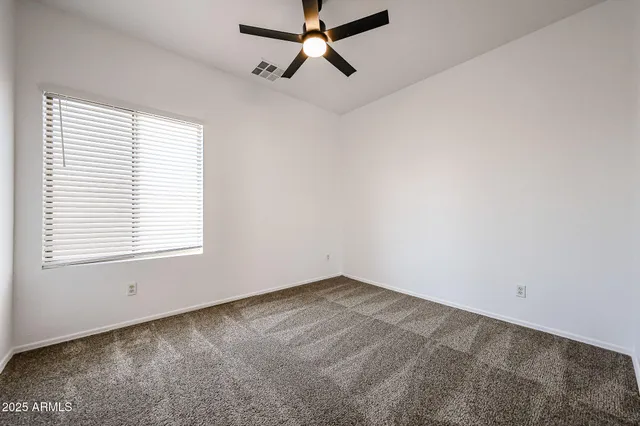 an empty room with a window and a fan