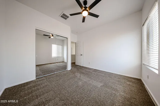 an empty room with windows and fan