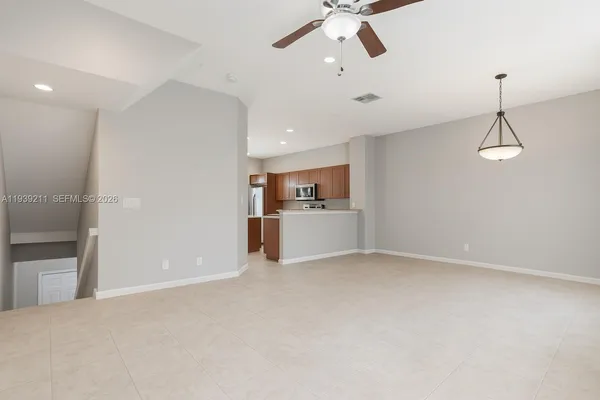 an empty room with chandelier fan and windows