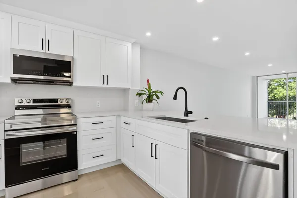 a kitchen with white cabinets a sink and appliances