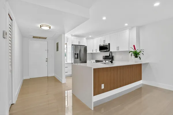 a view of kitchen with stainless steel appliances granite countertop a refrigerator a sink a stove a microwave and island