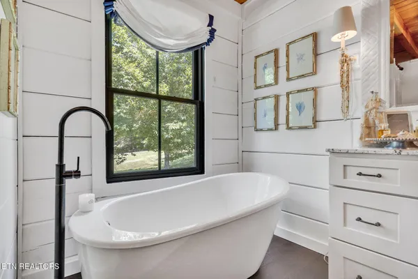 a spacious bedroom with a bed a dresser and next to a window