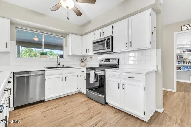 a kitchen with stainless steel appliances granite countertop a sink and cabinets with wooden floors