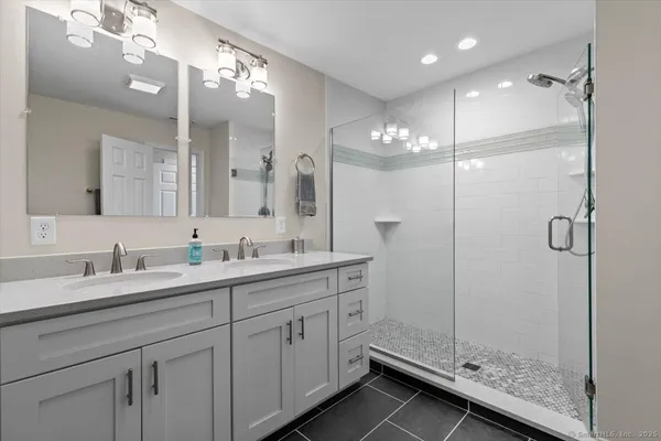 a bathroom with a double vanity sink mirror and shower