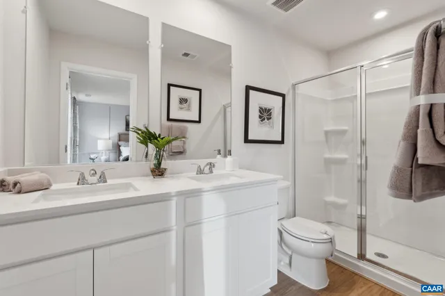 a bathroom with a toilet sink double vanity and shower