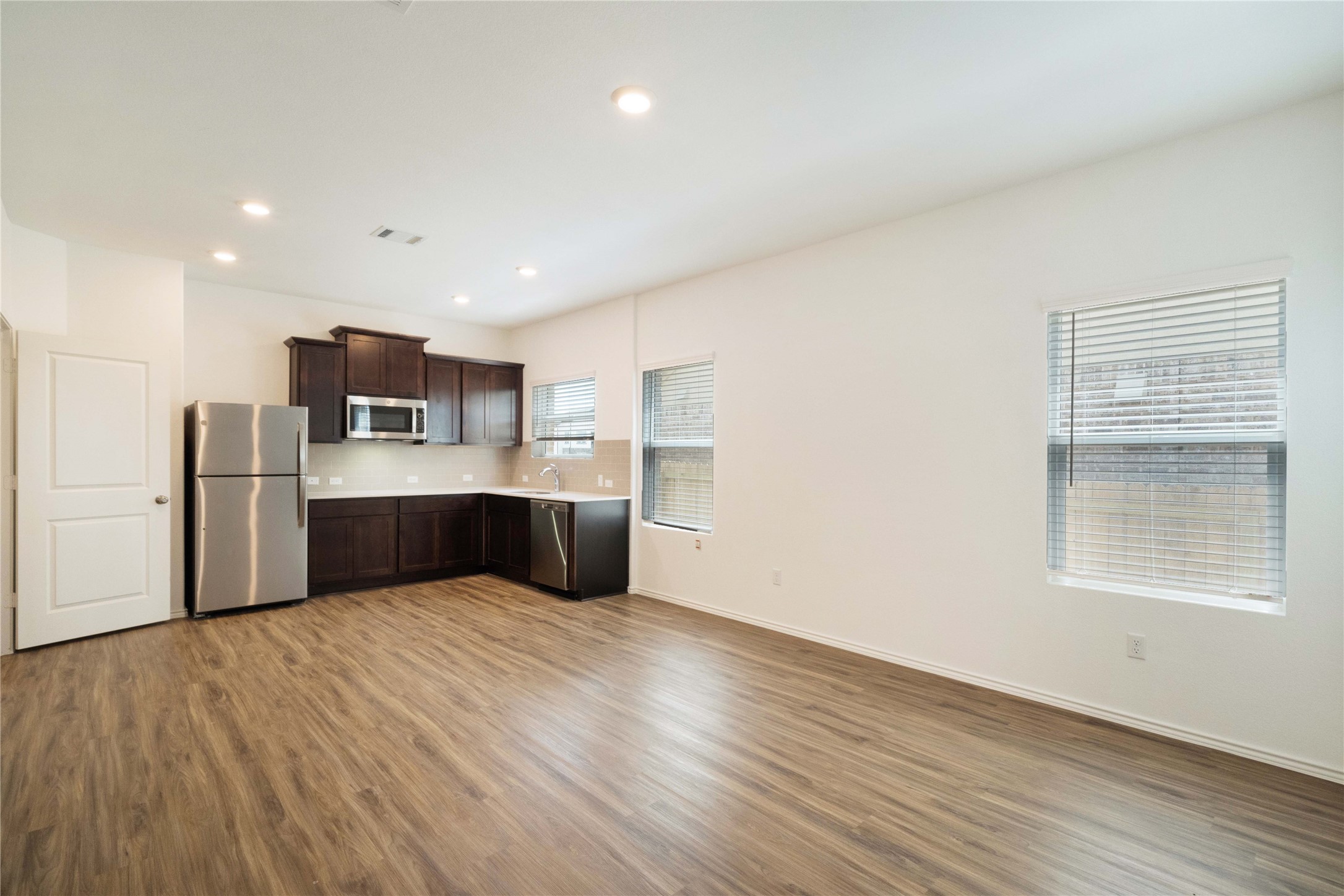 932 Mallow Road Leander, TX 78641 - Photo 23 of 40 a large white kitchen with a refrigerator a microwave oven a sink with wooden cabinets and wooden floor