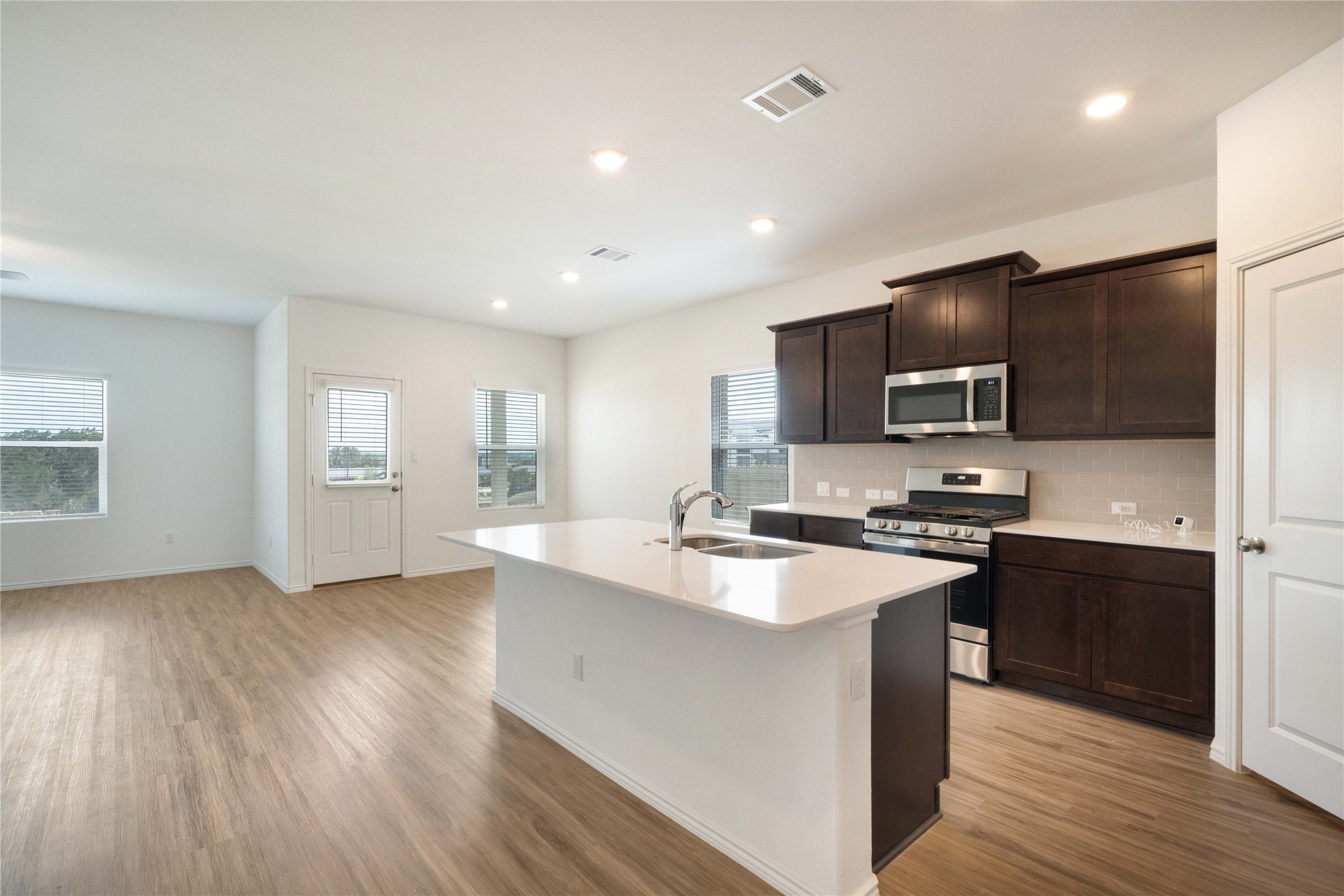 932 Mallow Road Leander, TX 78641 - Photo 8 of 40 a kitchen with stainless steel appliances a sink dishwasher a refrigerator a stove top oven a wooden floor and cabinets