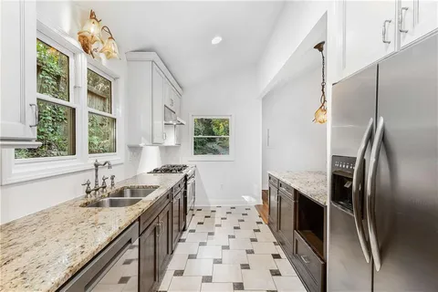 a kitchen with granite countertop a sink stove and refrigerator