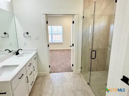 a bathroom with a double vanity sink and shower