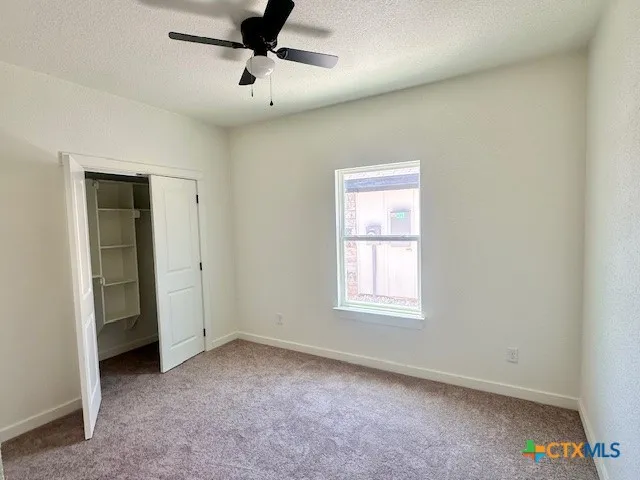 an empty room with windows and fan