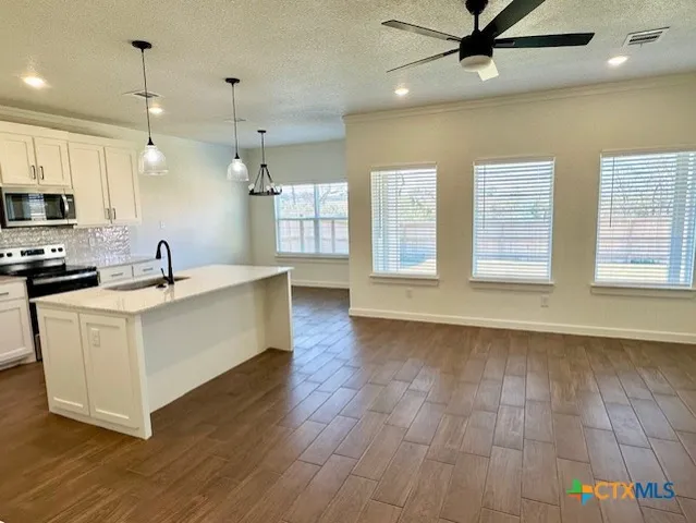 a large white kitchen with a large window a sink and stainless steel appliances
