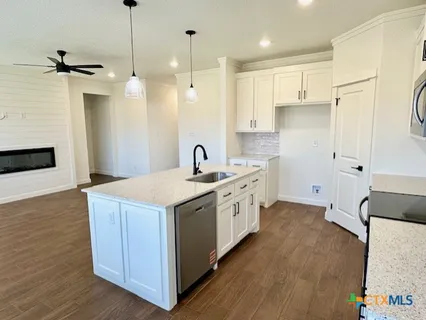a kitchen with stainless steel appliances a stove a sink a refrigerator and a oven with wooden floor
