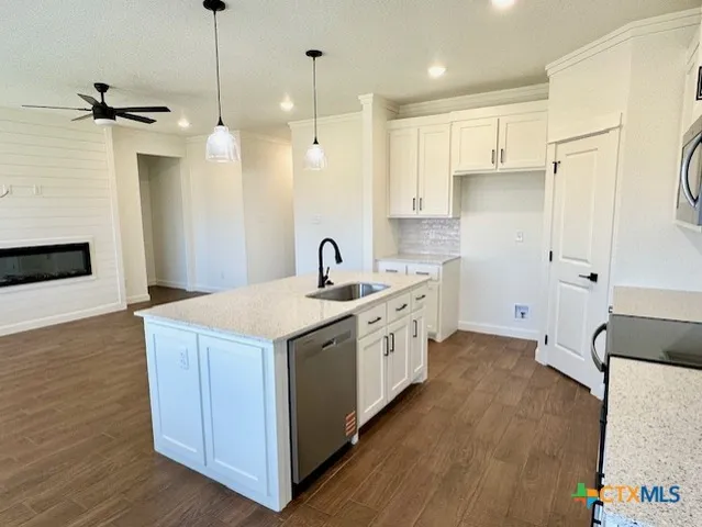 a kitchen with stainless steel appliances a stove a sink a refrigerator and a oven with wooden floor