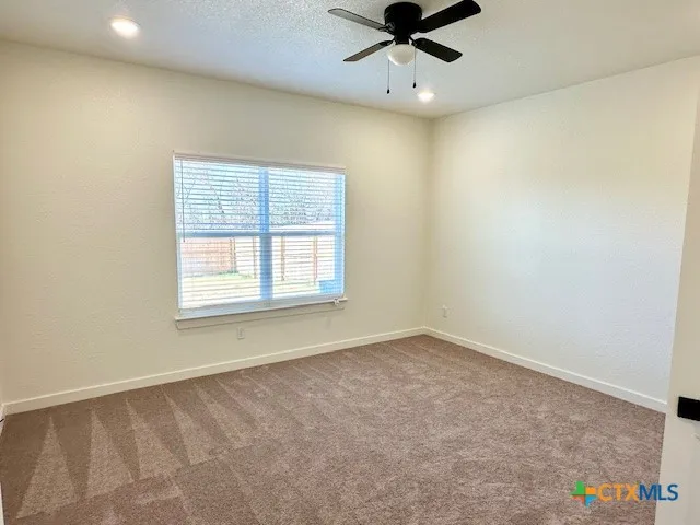 an empty room with a window and a fan