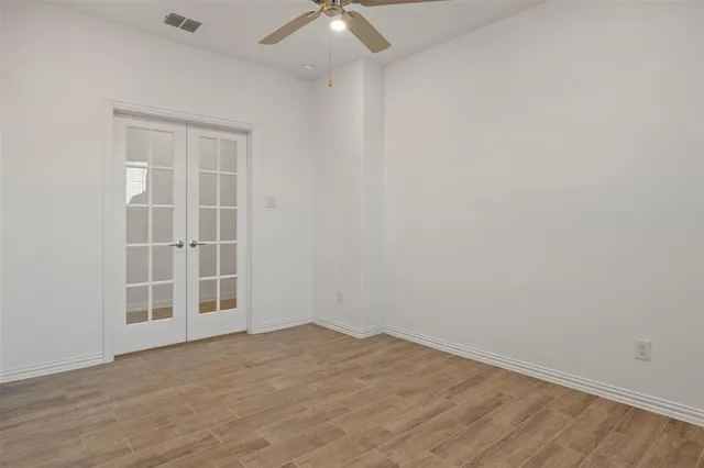 a view of empty room with wooden floor and fan