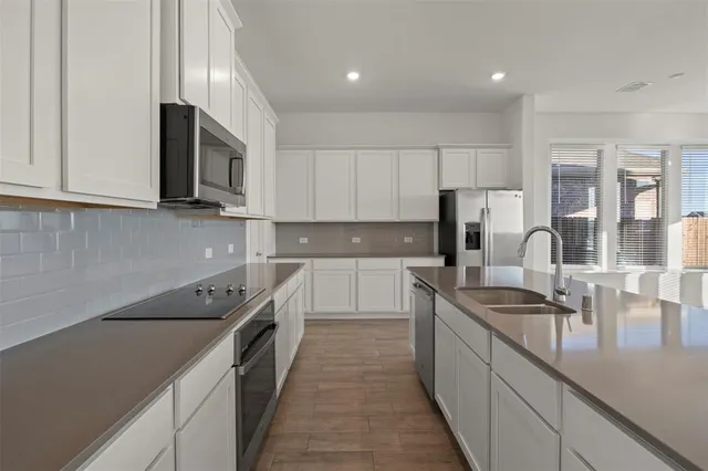 a kitchen with kitchen island granite countertop a sink stainless steel appliances and cabinets