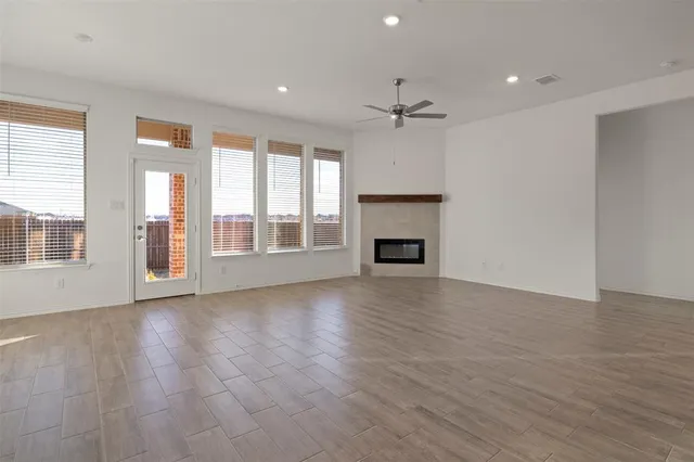 an empty room with wooden floor fireplace and windows