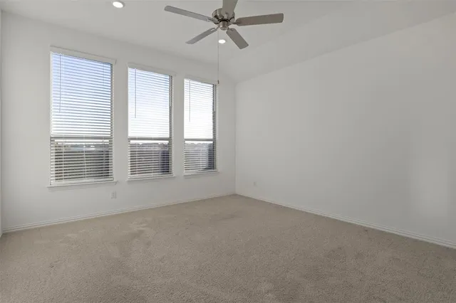 an empty room with chandelier fan and windows