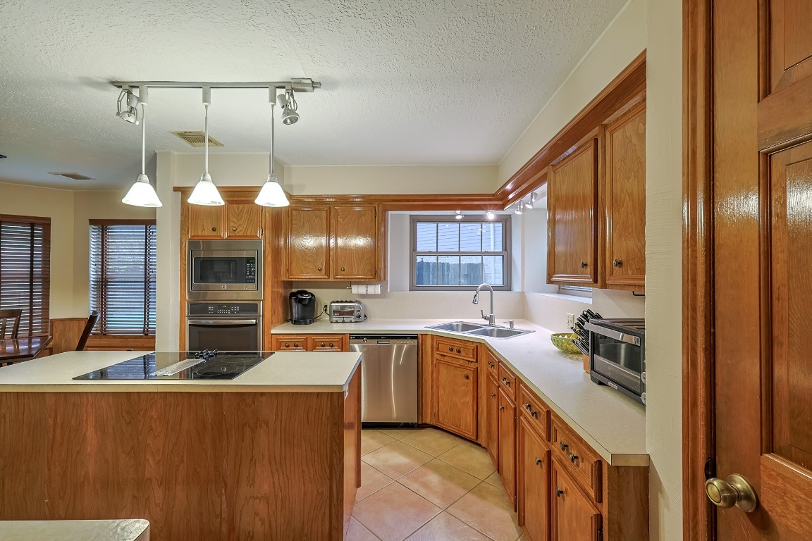 5527 Glenmere Lane Spring, TX 77379 - Photo 16 of 40 a kitchen with a sink dishwasher a stove and a refrigerator with wooden floor