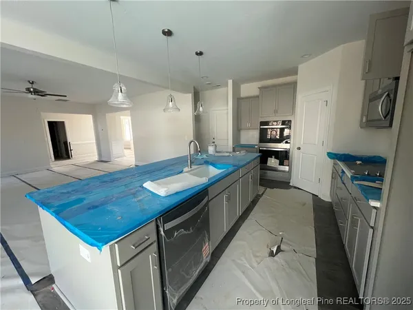 a kitchen with stainless steel appliances kitchen island a table chairs in it and wooden floors