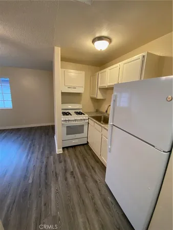a kitchen with a refrigerator a stove top oven and wooden floor