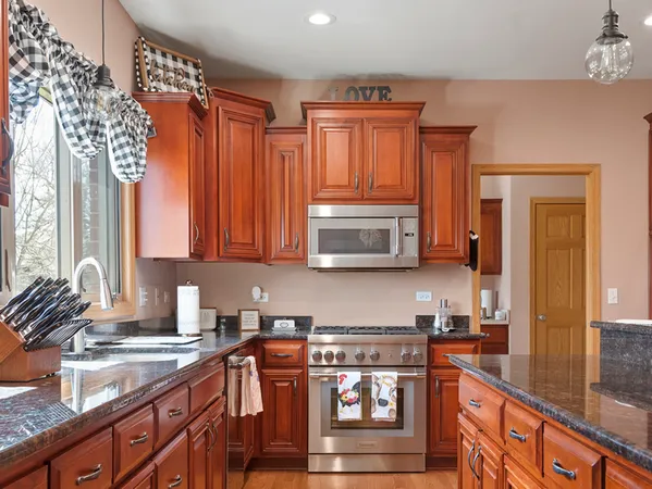 a kitchen with stainless steel appliances granite countertop a stove a sink and a microwave
