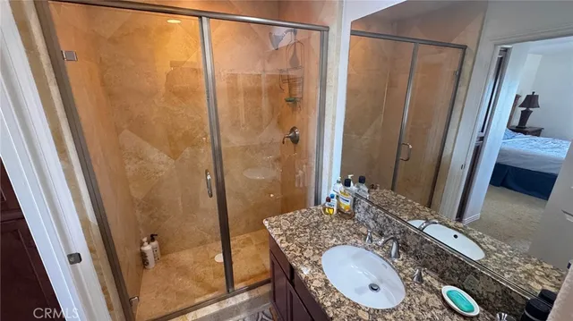 a bathroom with a granite countertop sink a mirror a vanity and shower