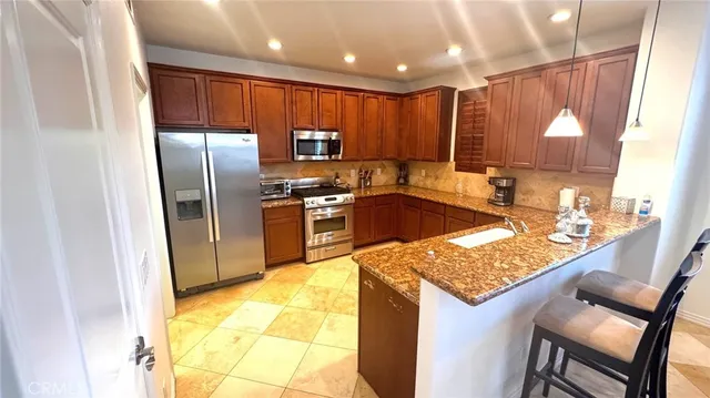 a kitchen with granite countertop stainless steel appliances a sink stove and refrigerator