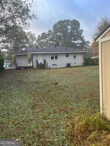 a view of a house with a dry yard and large tree