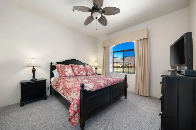 a spacious bedroom with a bed and a flat tv screen