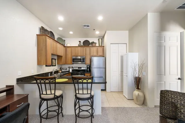 a kitchen with stainless steel appliances kitchen island granite countertop a refrigerator and a stove top oven