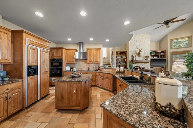 a kitchen with stainless steel appliances kitchen island granite countertop a sink stove and refrigerator