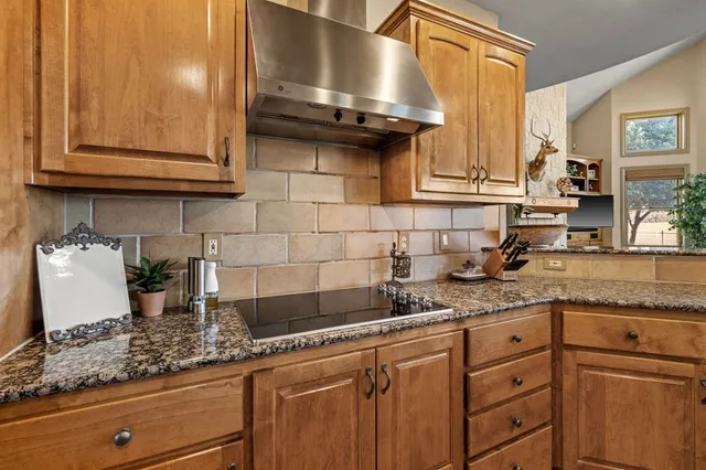 a kitchen with granite countertop a sink a stove and cabinets
