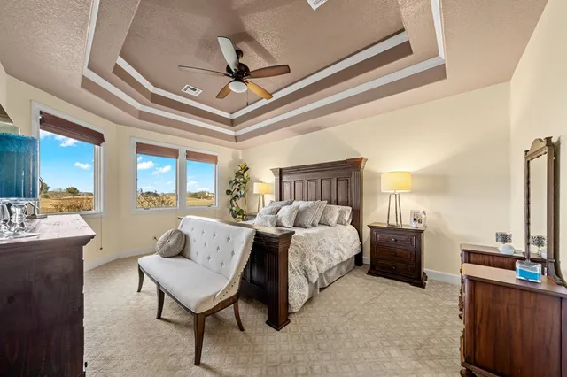 a spacious bedroom with a bed a couch and a ceiling fan