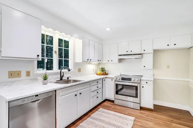 a kitchen with a sink white cabinets and white appliances