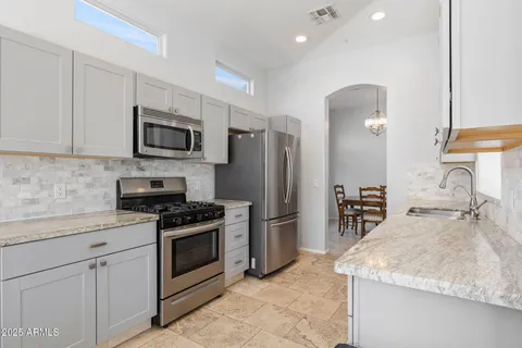 a kitchen with kitchen island granite countertop a stove sink and refrigerator