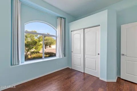 an empty room with wooden floor closet and windows